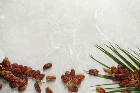 Tasty sweet dried dates and palm leaf on gray table, flat lay. Space for textの写真素材