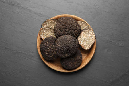Black truffles in wooden plate on gray table, top viewの写真素材