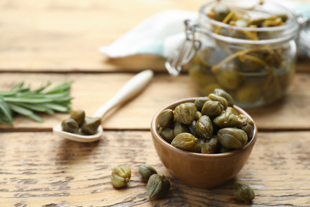 Delicious pickled capers on wooden table, space for textの写真素材