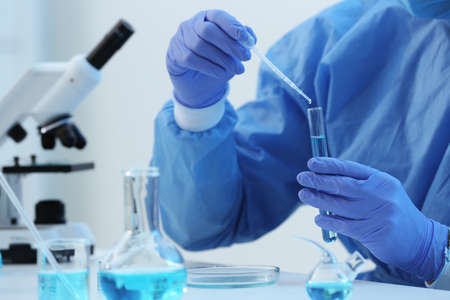 Scientist dripping sample into test tube in laboratory, closeup. Medical research