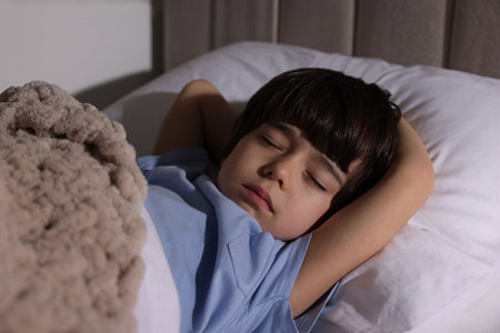 Cute little boy sleeping in bed at home