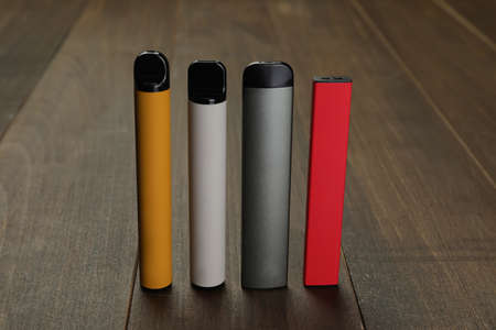 Many different electronic cigarettes on wooden table