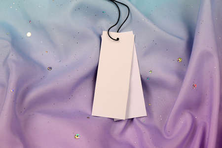 Blank white tags on color fabric, top view. Space for textの写真素材
