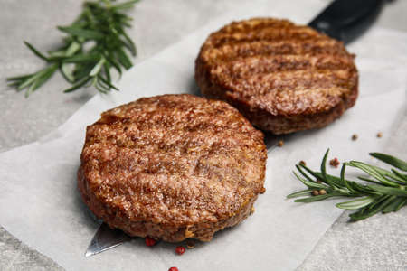 Tasty grilled hamburger patties, knife and seasonings on gray table, closeupの写真素材