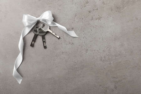Keys with white bow on gray table, top view and space for text. house warming party