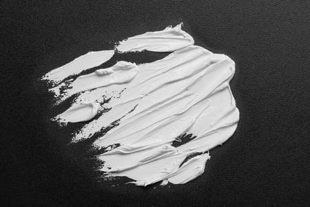 Strokes of white oil paint on black canvas, top viewの写真素材