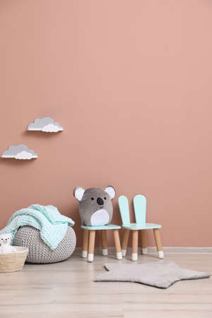 Child's toys, pouf and chairs near pink wall indoors. interior designの写真素材