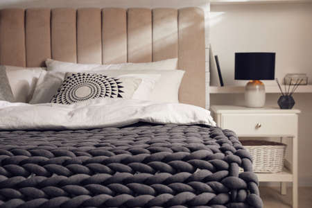 Soft chunky knit blanket on bed in stylish room interiorの写真素材