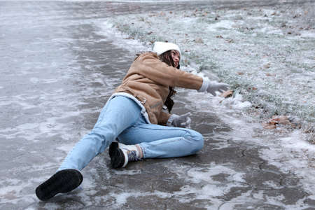 Young woman fallen on slippery icy pavement outdoorsの写真素材
