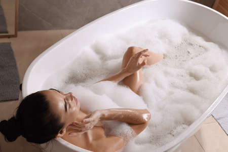 Woman taking bath with shower gel indoors, above viewの写真素材