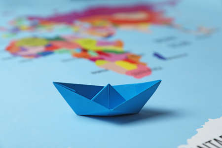 Light blue paper boat on world map, closeup