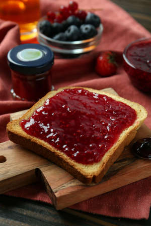 Delicious toast with jam on wooden board, closeup