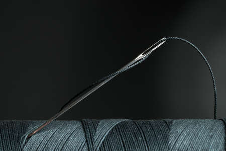 Black sewing thread with needle on dark background, closeupの写真素材