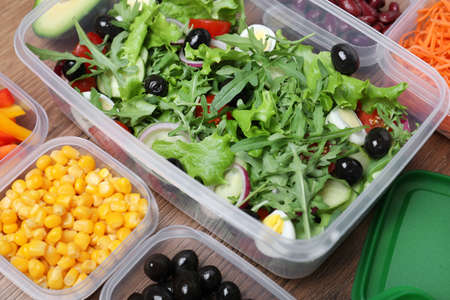 Set of plastic containers with fresh food on wooden table