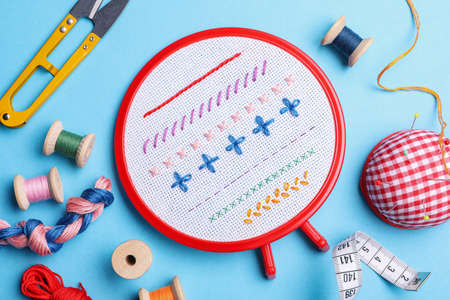 Flat lay composition with embroidery and different sewing accessories on light blue background