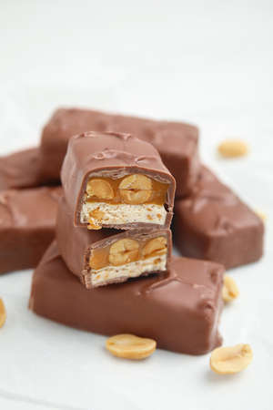 Chocolate bars with caramel, nuts and nougat on white table, closeup