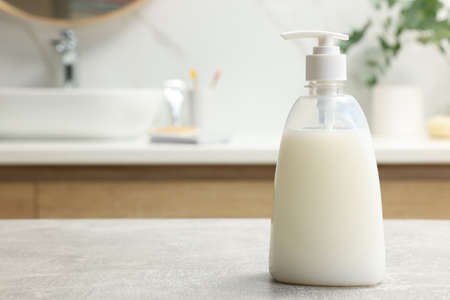 Dispenser of liquid soap on light gray table in bathroom, space for textの写真素材