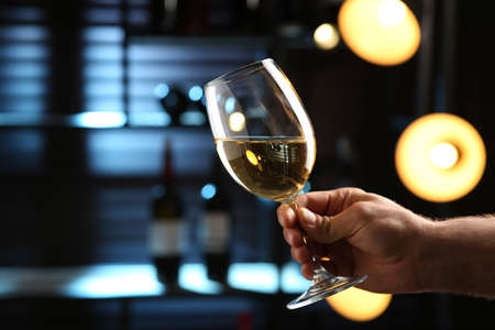 Man with glass of white wine indoors, closeup. Space for textの写真素材