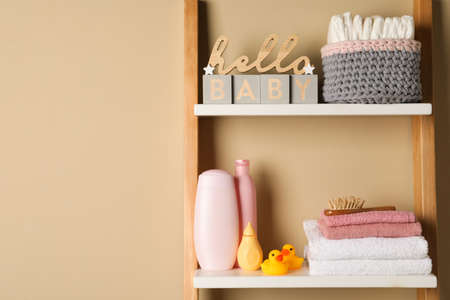 Towels, toys and baby accessories on wooden rack, space for textの写真素材