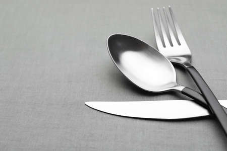 Set of shiny silver cutlery on gray table, closeup. Space for text