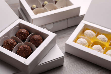Many delicious candies in boxes on white wooden table. production line