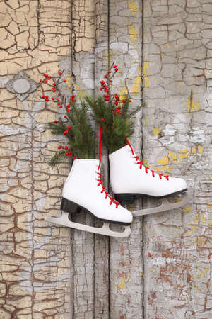 Pair of ice skates with Christmas decor hanging on old wooden doorの写真素材