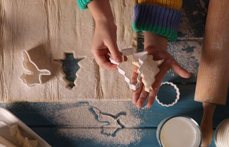 Little child making Christmas cookies at blue wooden table, top viewの写真素材