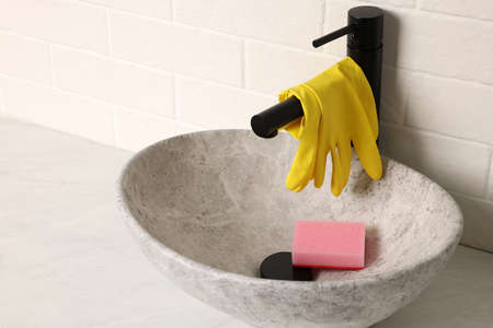Rubber gloves on faucet in bathroom sinkの写真素材