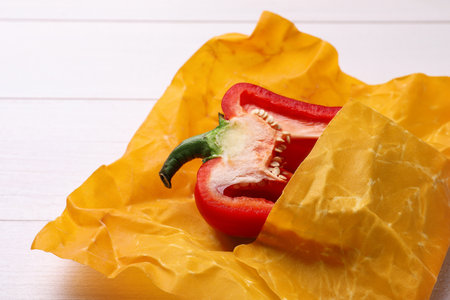 Half of bell pepper in beeswax food wrap on white wooden table, closeupの写真素材