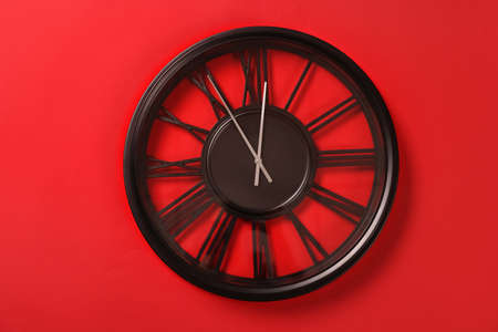 Clock showing five minutes until midnight on red background. New Year count down
