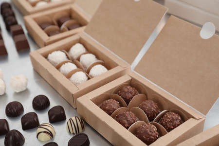 Different delicious chocolate candies and boxes on white table. production line