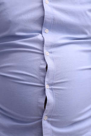 Man wearing tight shirt, closeup view. overweight problem