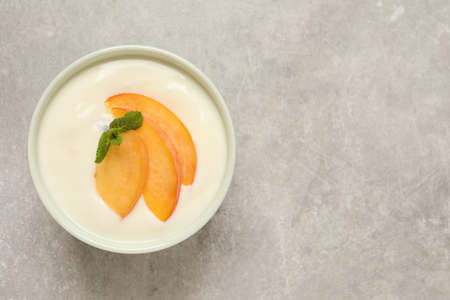 Delicious yogurt with fresh peach and mint on gray table, top view. Space for textの写真素材