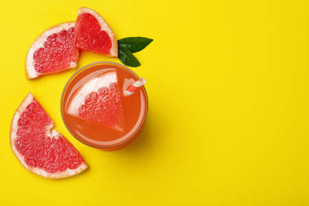 Tasty freshly made grapefruit juice and fruit on yellow background, flat lay. Space for textの写真素材