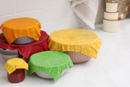 Different dishware covered with beeswax food wraps on white marble table. Space for textの写真素材