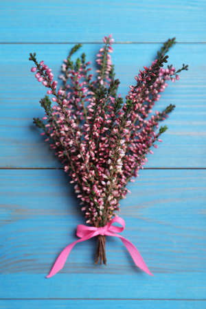 Bunch of heather branches with beautiful flowers and ribbon on light blue wooden table, top viewの写真素材
