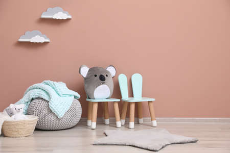 Child's toys, pouf and chairs near pink wall indoors. interior designの写真素材