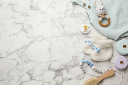 Cute baby stuff on white marble background, flat lay. Space for textの写真素材