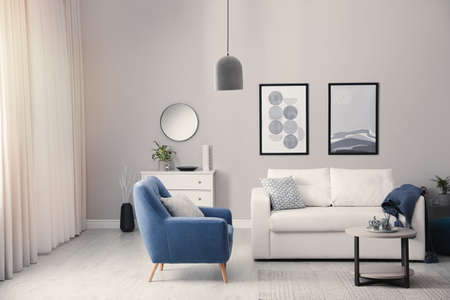 Stylish living room interior with white sofa, armchair and small coffee table