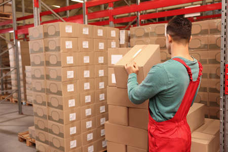 Worker stacking cardboard boxes in warehouse. Wholesalingの写真素材