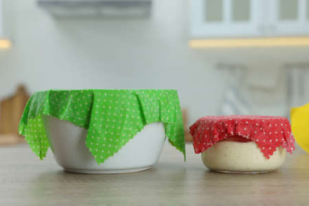Bowls covered with beeswax food wraps on wooden table in kitchenの写真素材