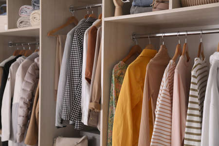 Wardrobe closet with different stylish clothes, accessories and home stuff