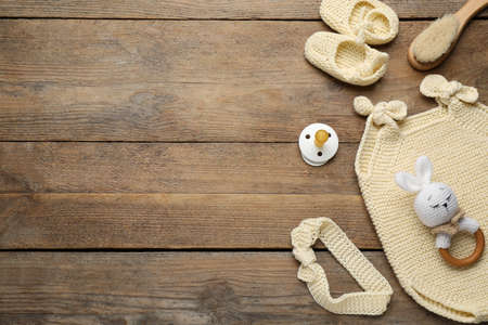 Cute baby stuff on wooden background, flat lay. Space for text