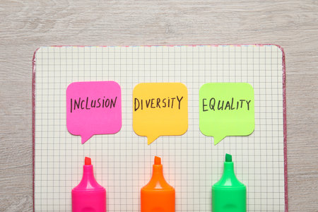 Sticky notes with words Diversity, Equality, Inclusion, markers and notebook on wooden table, top viewの写真素材