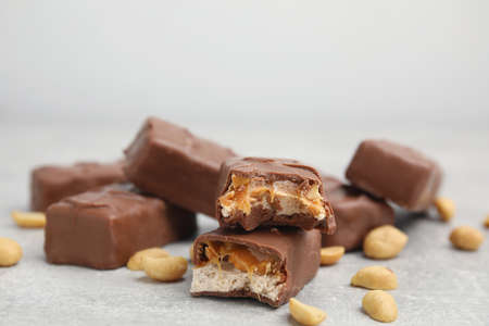Chocolate bars with caramel, nuts and nougat on light gray table, closeup