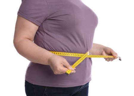 Overweight woman measuring waist with tape on white background, closeupの写真素材