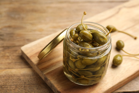 Jar of capers on wooden table, closeup. Space for textの写真素材