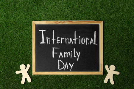 Chalkboard with text International Family Day and wooden figures on green grass, flat layの写真素材