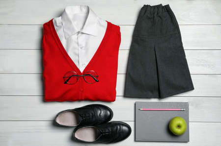Stylish school uniform for girl, stationery and apple on white wooden background, flat layの写真素材