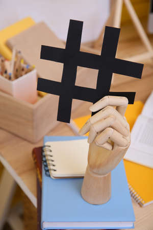 Wooden mannequin hand with paper hashtag symbol indoorsの写真素材